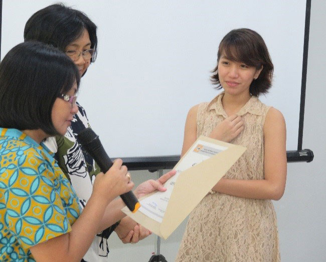  Prof. Maria Paz N. Marquez reads the certificate  as Prof. Grace T. Cruz (middle) and Ms. Musni look on