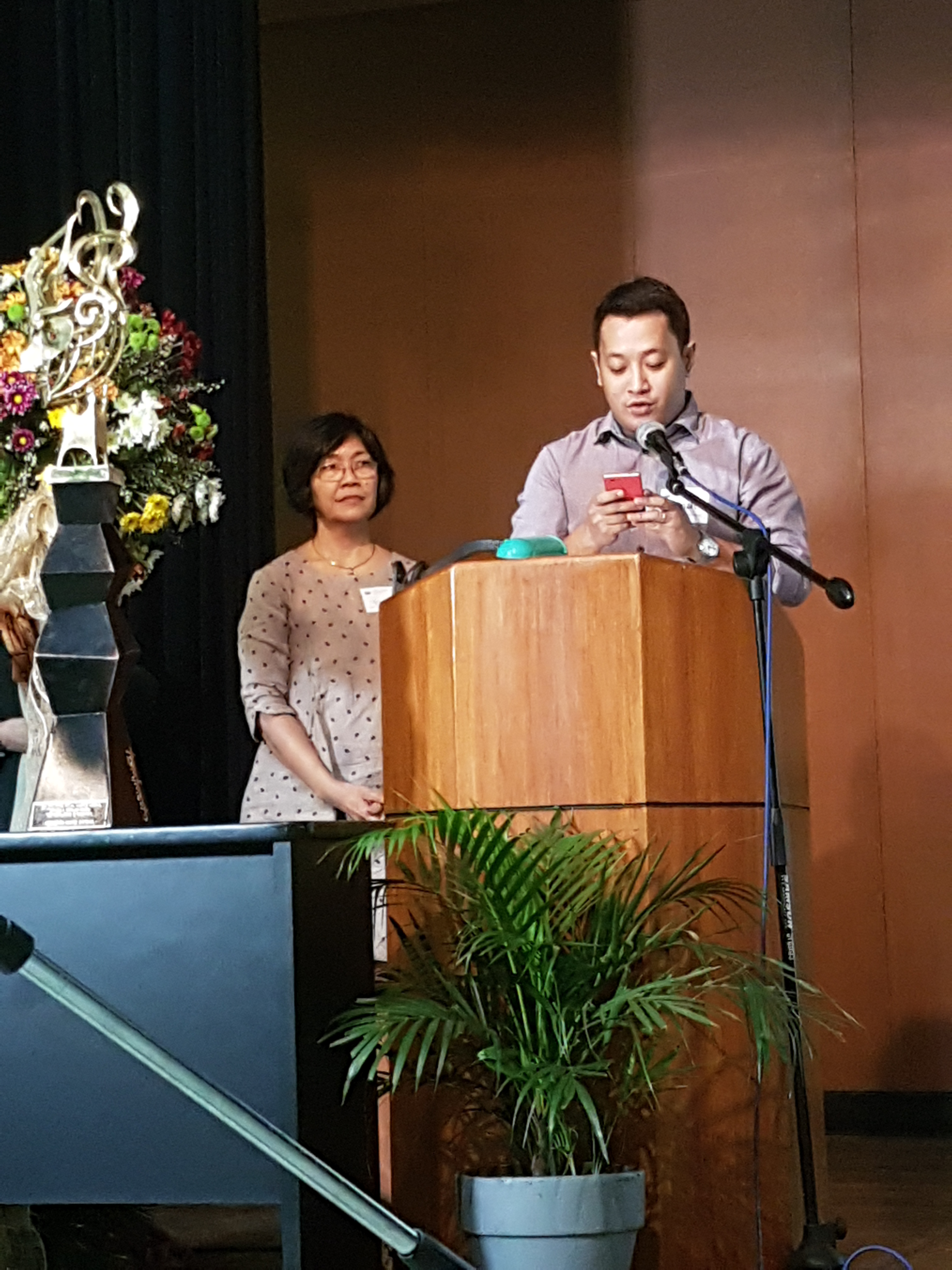 <br />
Mr. Emmanuel B. Garcia of the UP Department of Geography reads Dr. Ortega’s message as Prof. Grace T. Cruz looks on.